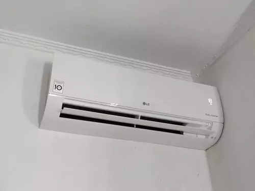 LG Dual Inverter instalado no alto de parede branca, com aletas abertas