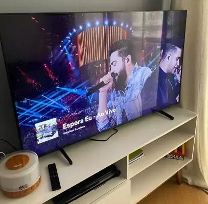 Samsung BU8000 em cima de rack com show de dupla sertaneja sendo exibido na tela.