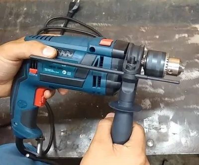 Homem segurando a Bosch GSB 16 em cima de mesa de manutenção