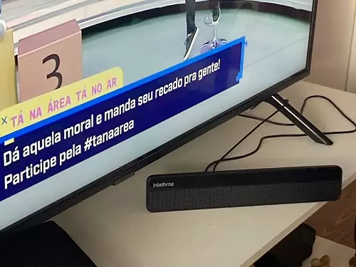 Intelbras AI3101 em cima de estante branca em frente a TV.