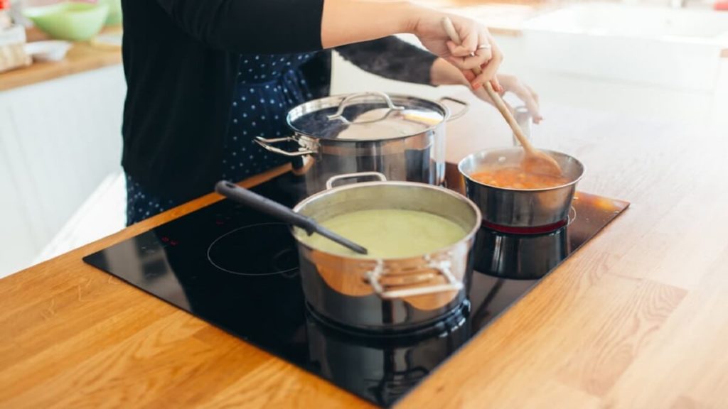 Abertura do post sobre cooktop a gás ou indução: Homem cozinhando em cooktop de indução