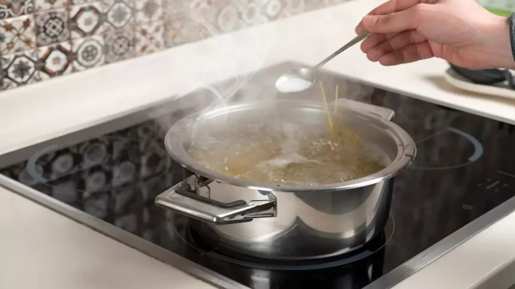 Homem cozinhando macarrão em um fogão de indução